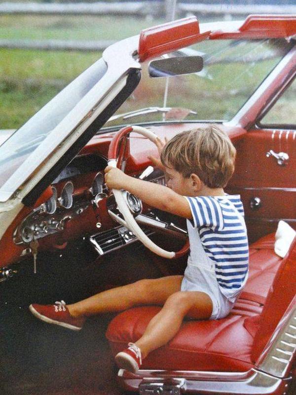 John F. Kennedy, Jr takes the wheel of a car back in 1963.