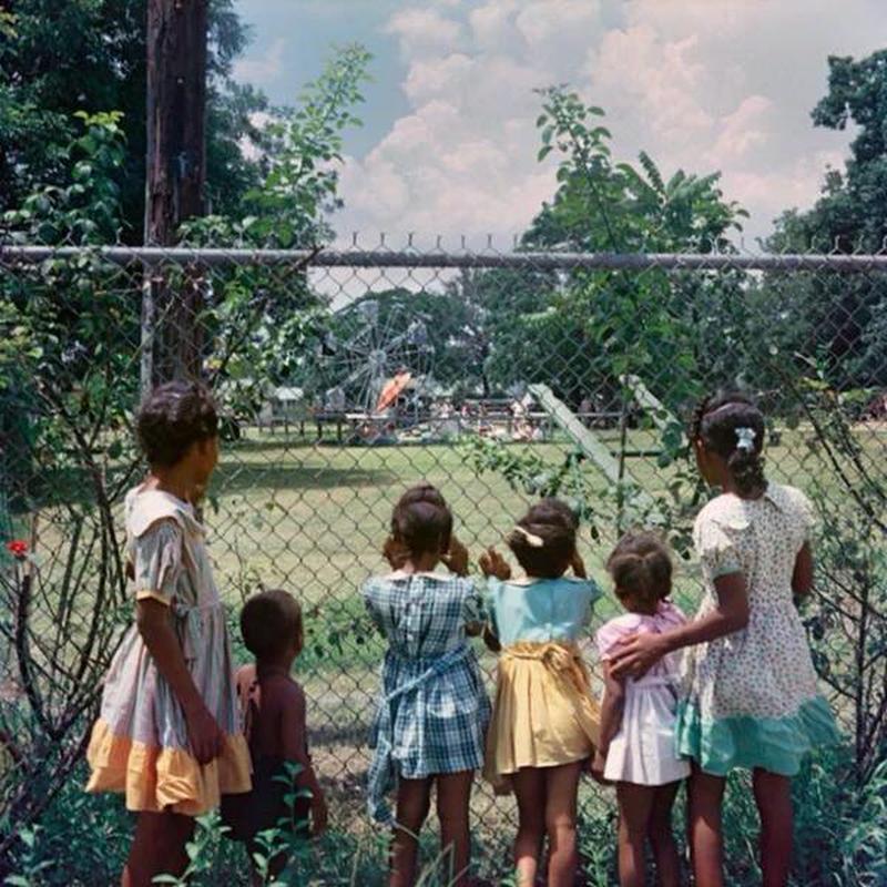 Black children witness white children playing in segregated park, 1956