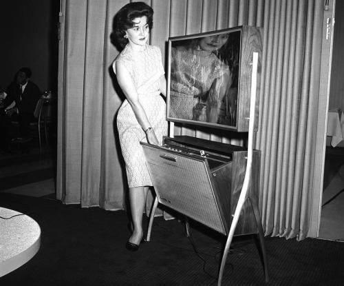 The Future Unveiled: At the 1961 Home Furnishings Market in Chicago, a cutting-edge 4-inch thick TV screen with built-in recording feature emerges.