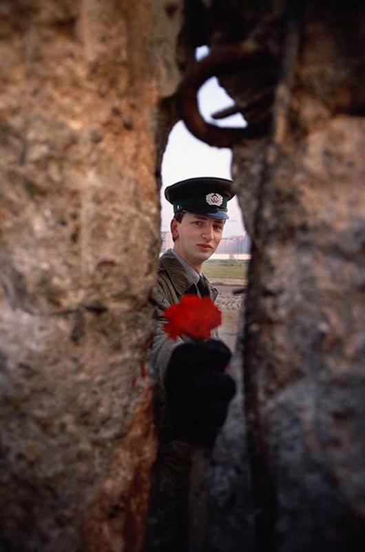East German Soldier Offers a Flower through the Berlin Wall, Moments Before Its Demolition in 1989