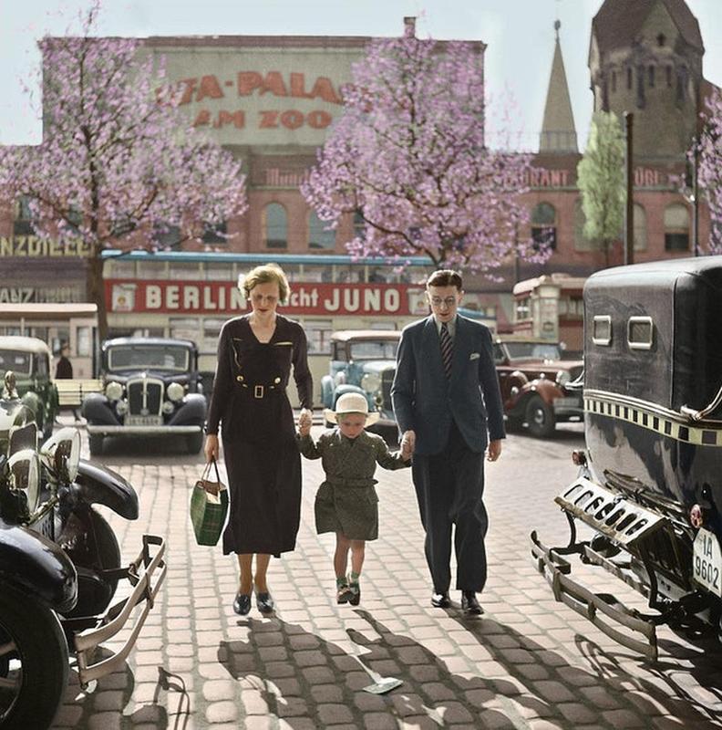 Family strolling amidst taxicabs outside Ufa-Palast cinema. Berlin, 1929.