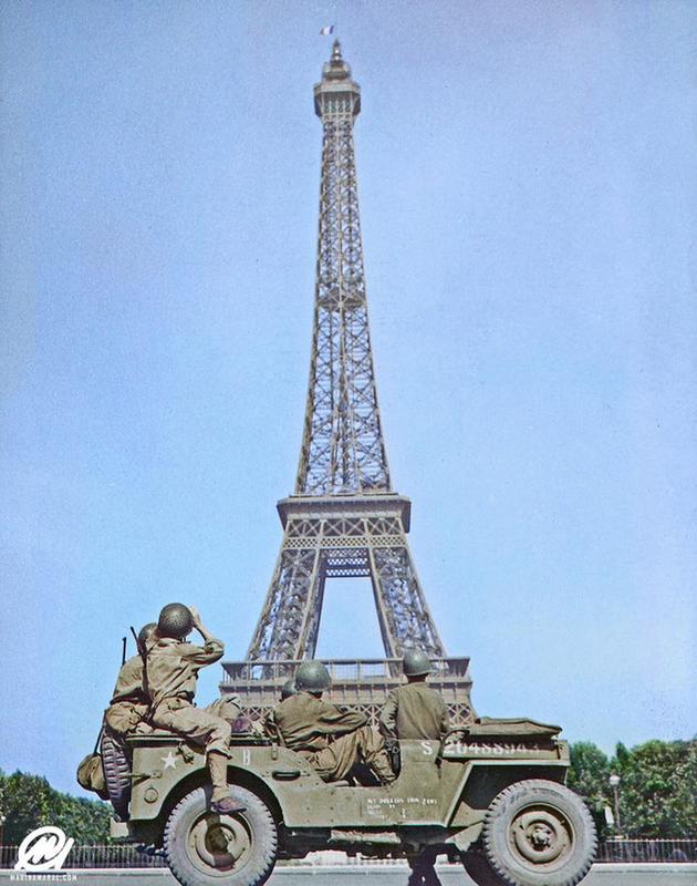 American soldiers witness the Tricolor being raised on the Eiffel Tower once more, around August 25, 1944, in Paris, France.