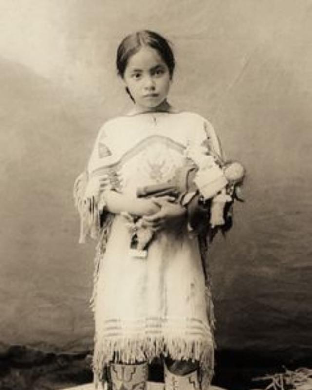 Child from the Sioux tribe poses with a doll in 1890