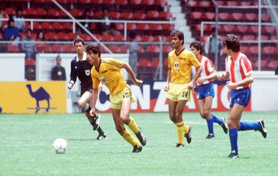 Iraq's Natiq Hashim makes progress with the ball in Iraq's inaugural FIFA World Cup game against Paraguay in 1986, risking harsh consequences from Uday Hussein in case of defeat.