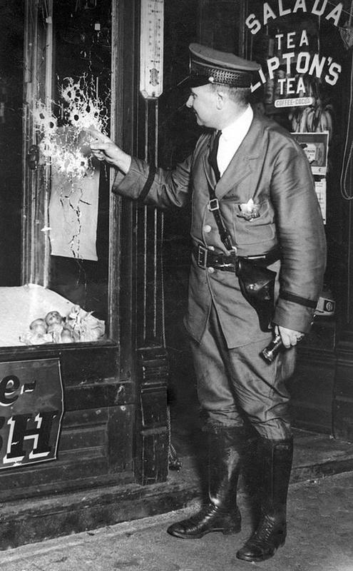 Chicago Police Officer Examines Multiple Bullet Holes in 1920s Murder Scene Window