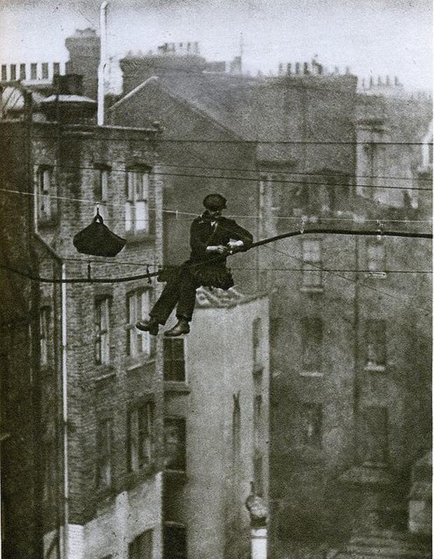 Nonchalantly, a telephone engineer in London effortlessly attaches a phone cable 50 feet above ground.