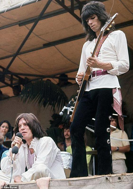 Mick Jagger of The Rolling Stones sits on stage as Keith Richards performs beside him during their free Hyde Park concert in London, captured in Alec Byrne's photo from July 1969.